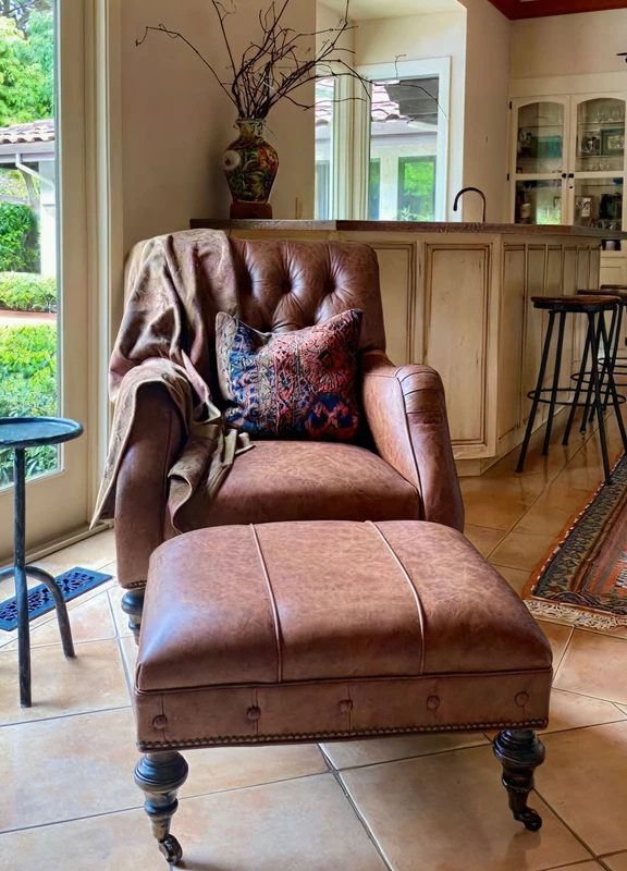 Brown tufted leather chair and ottoman in a bright sitting area