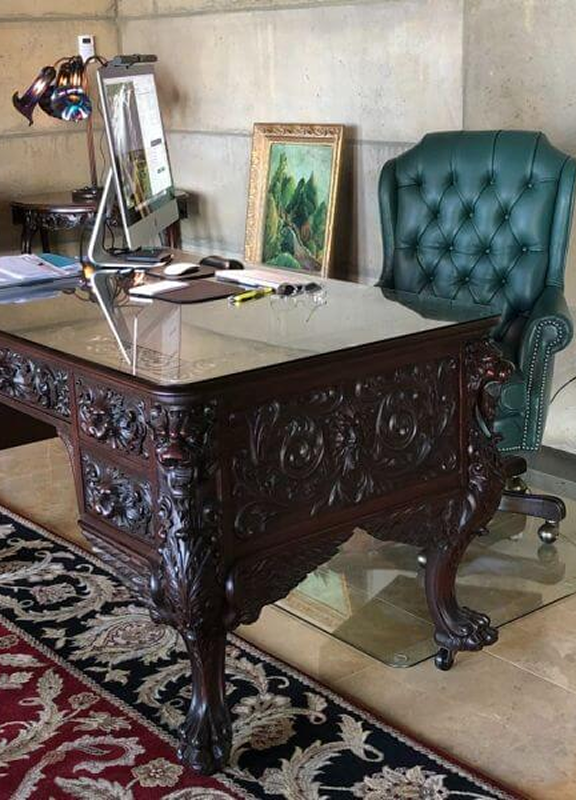 Carved wood desk with a green tufted leather chair